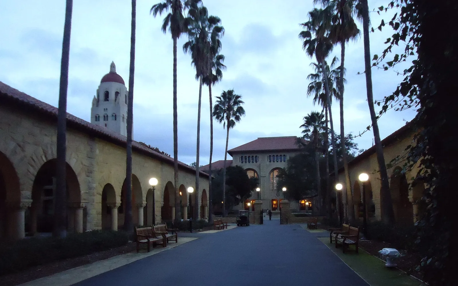 Stanford University campus with red-tile roofed buildings and palm trees on an expansive green lawn
